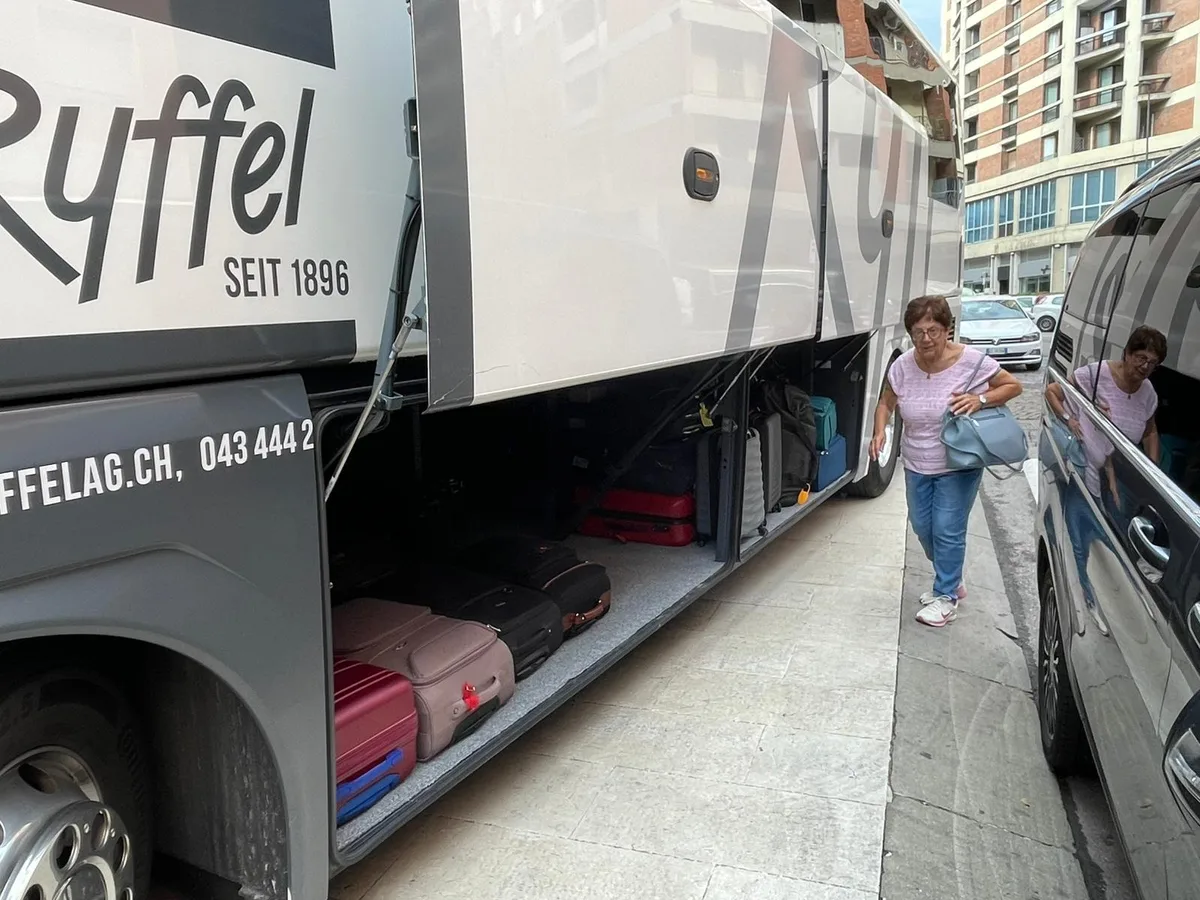 Eine Frau geht zwischen einem Reisebus und einem Van durch. 